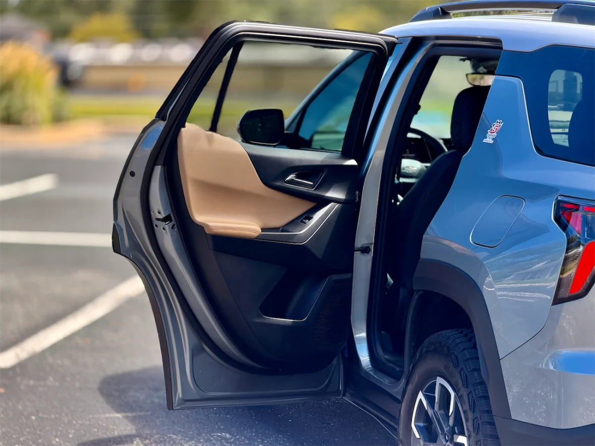 A car door opened, showing the interior with a beige and black color scheme, parked on a street.