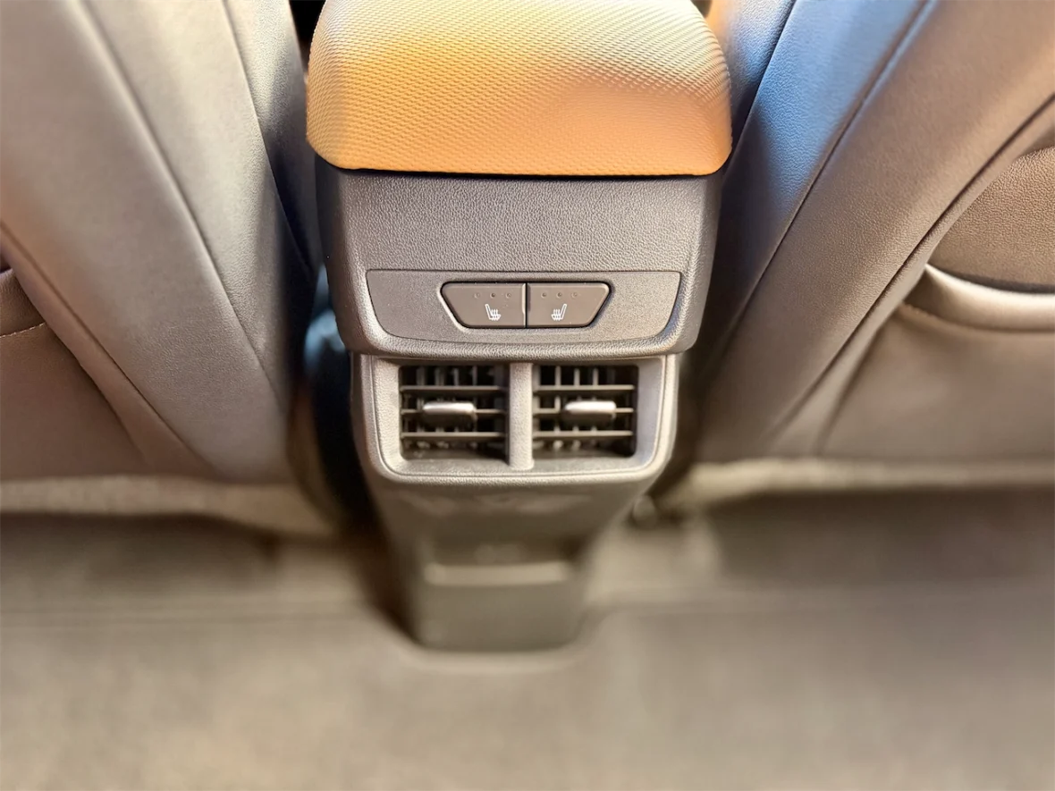 Close-up view of a car's rear seat control panel featuring heated seat buttons and air conditioning vents.