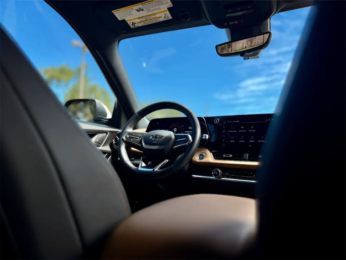 Interior view of a car focusing on the steering wheel and dashboard with a clear blue sky in the background.