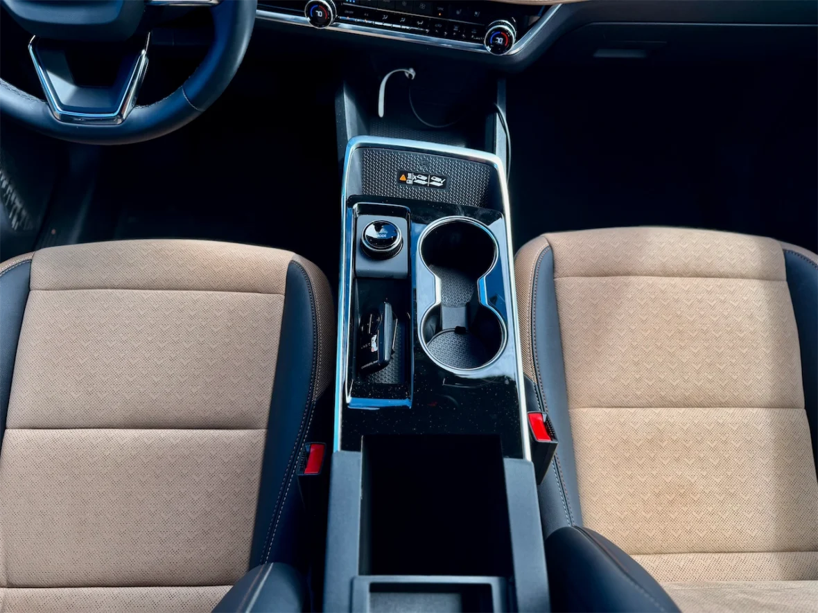 Overhead view of a car interior, showcasing the dashboard, steering wheel, and center console with cup holders and gear selector.
