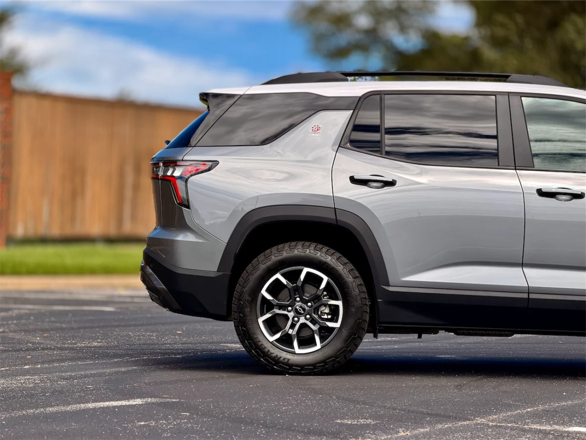 Side view of a modern gray SUV parked on a paved surface with a clear blue sky in the background.
