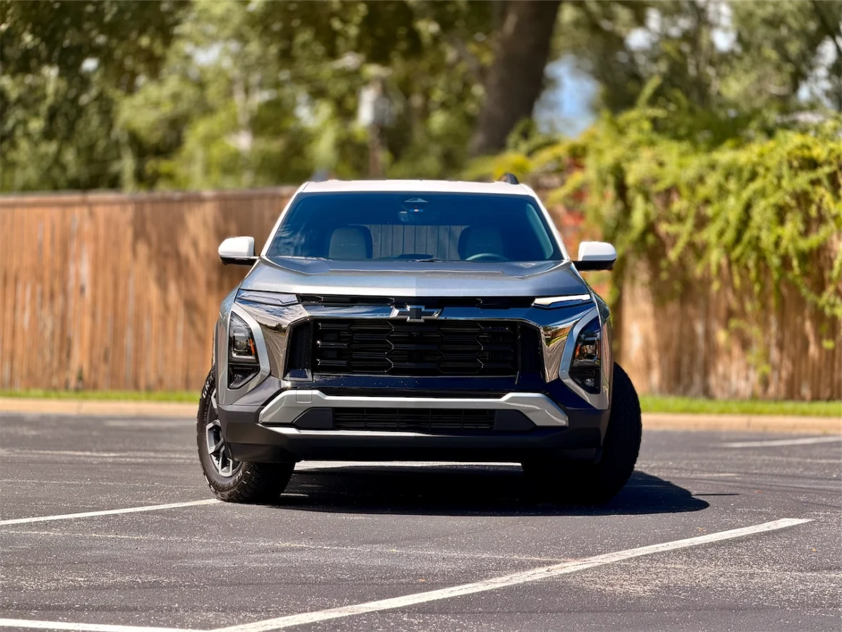 Front view of a modern SUV parked in an outdoor lot with a wooden fence in the background.