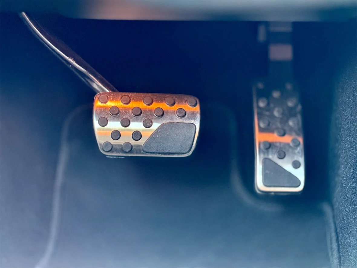 Close-up view of two car pedals, featuring a metallic design with textured surfaces.