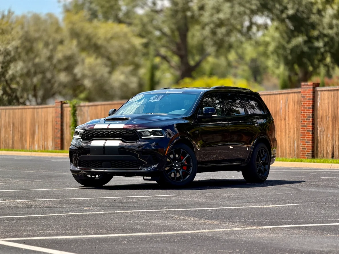 A black SUV parked in an empty lot, featuring a stylish design with racing stripes and black wheels.