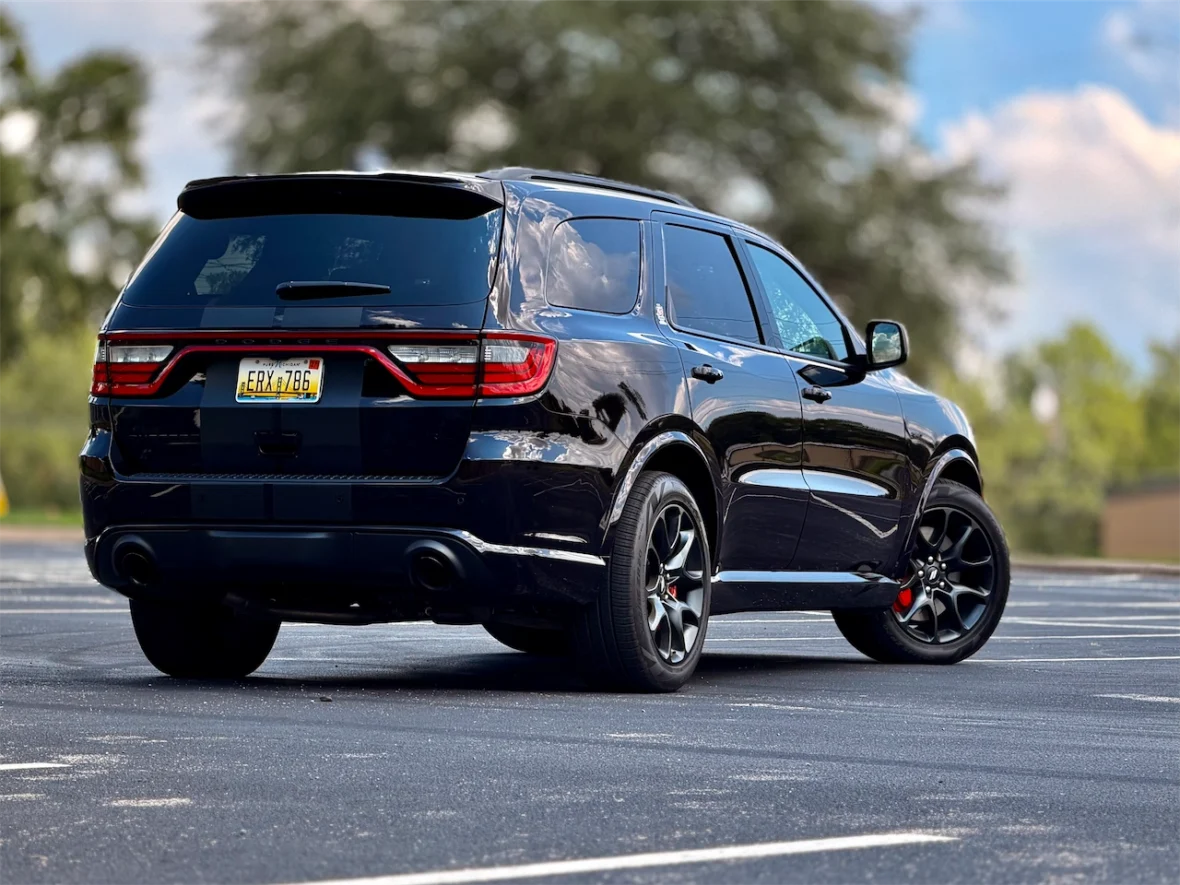 A black SUV parked in an empty lot, viewed from the rear with a clear sky in the background.