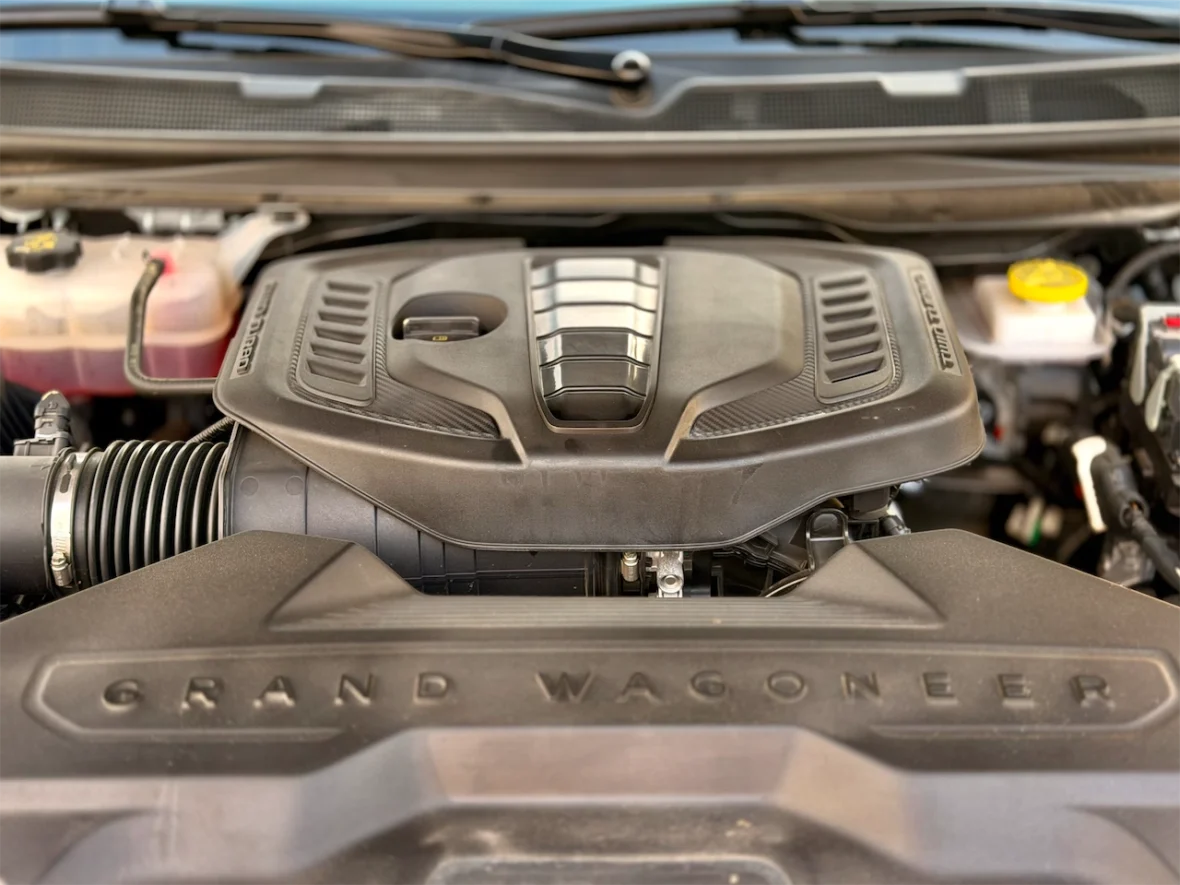 Close-up view of a car engine with 'GRAND WAGONEER' embossed on the engine cover.
