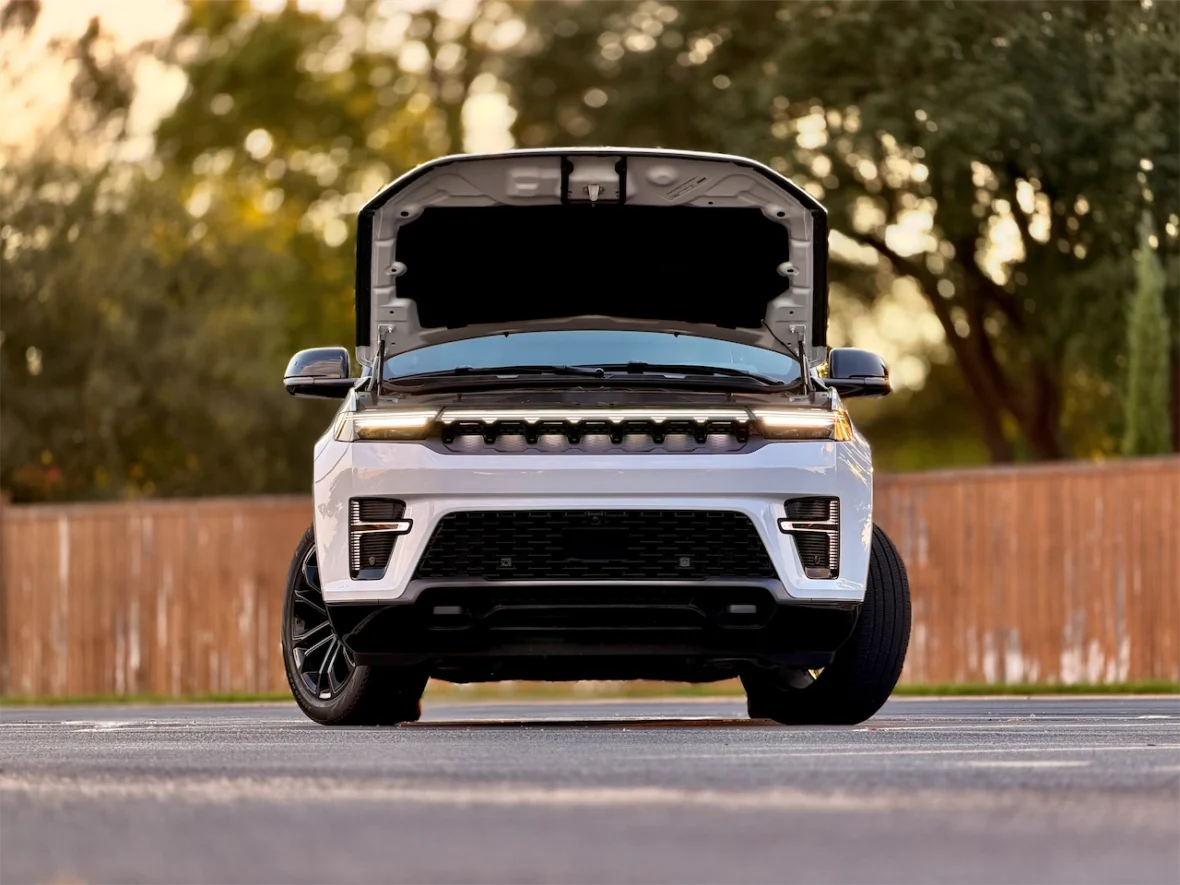 Front view of a car with its hood raised, showcasing the engine compartment, in an outdoor setting.