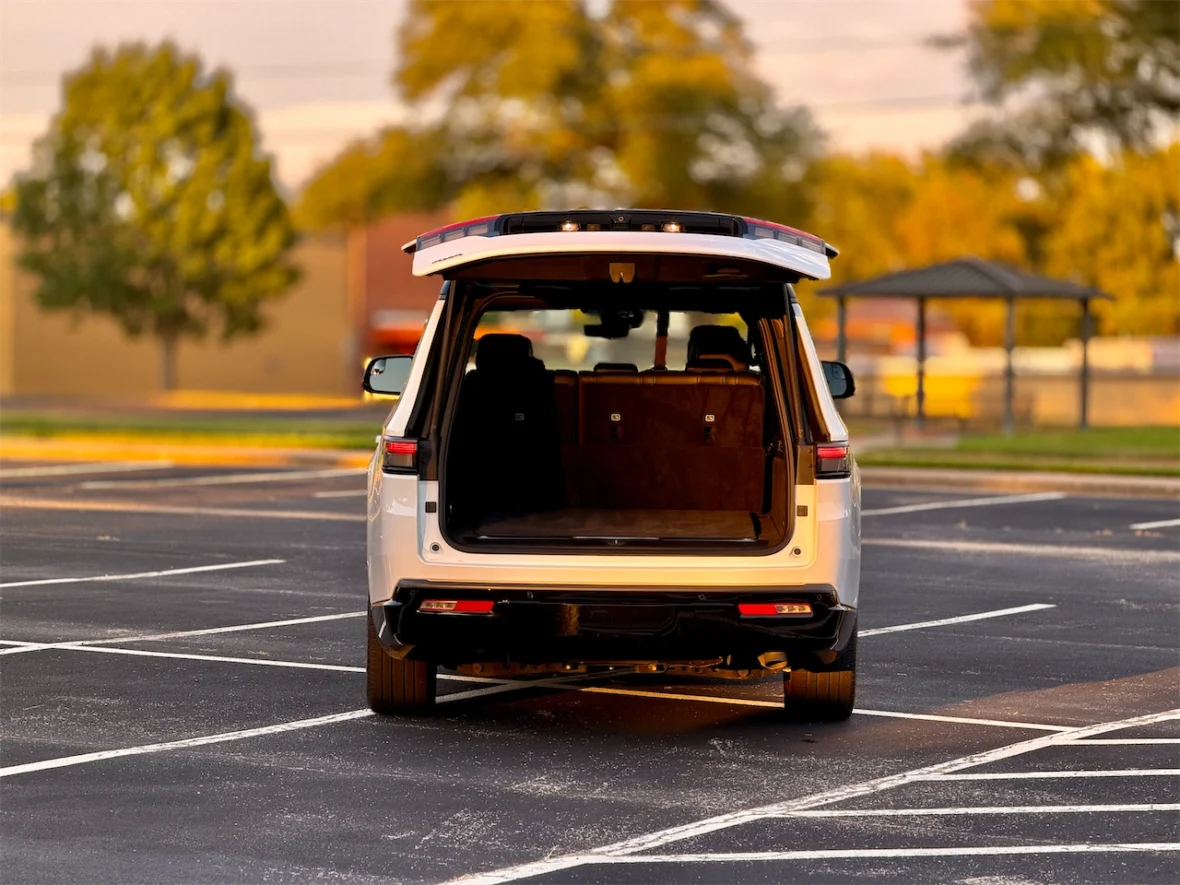 A rear view of the 2026 Jeep Grand Wagoneer L with the trunk open, parked in an empty parking lot during sunset.