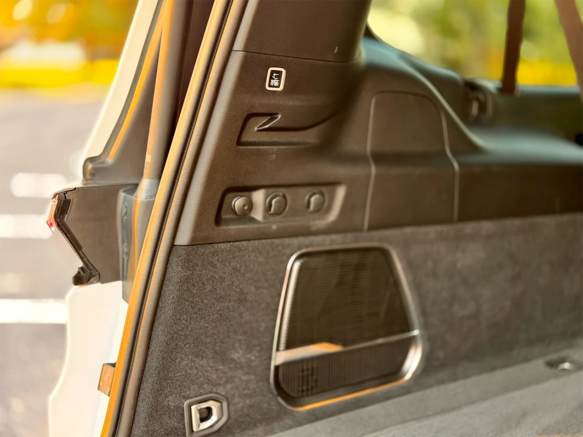 Interior door panel of a vehicle showing window control buttons and a speaker grill.