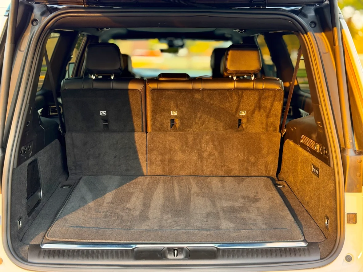 Interior view of a vehicle's trunk space showing plush carpeting and folded rear seats.