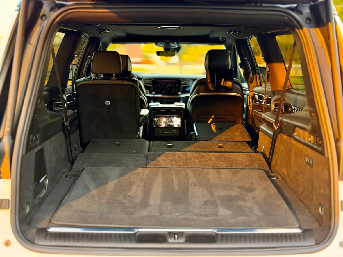 Interior view of the rear cargo space of an SUV with seats folded down, featuring a spacious, carpeted area.