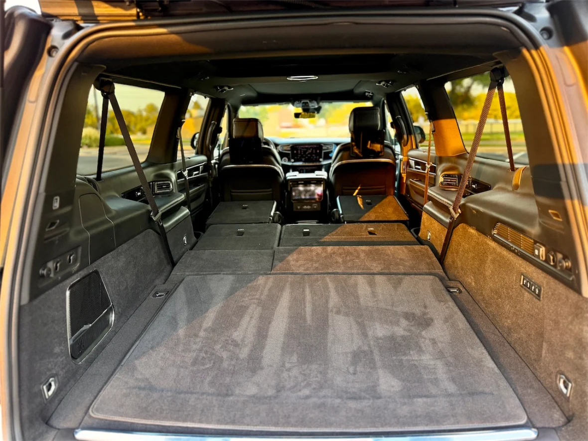 Interior view of a spacious SUV trunk with folded rear seats, showcasing a clean, carpeted floor and a view toward the front seats.