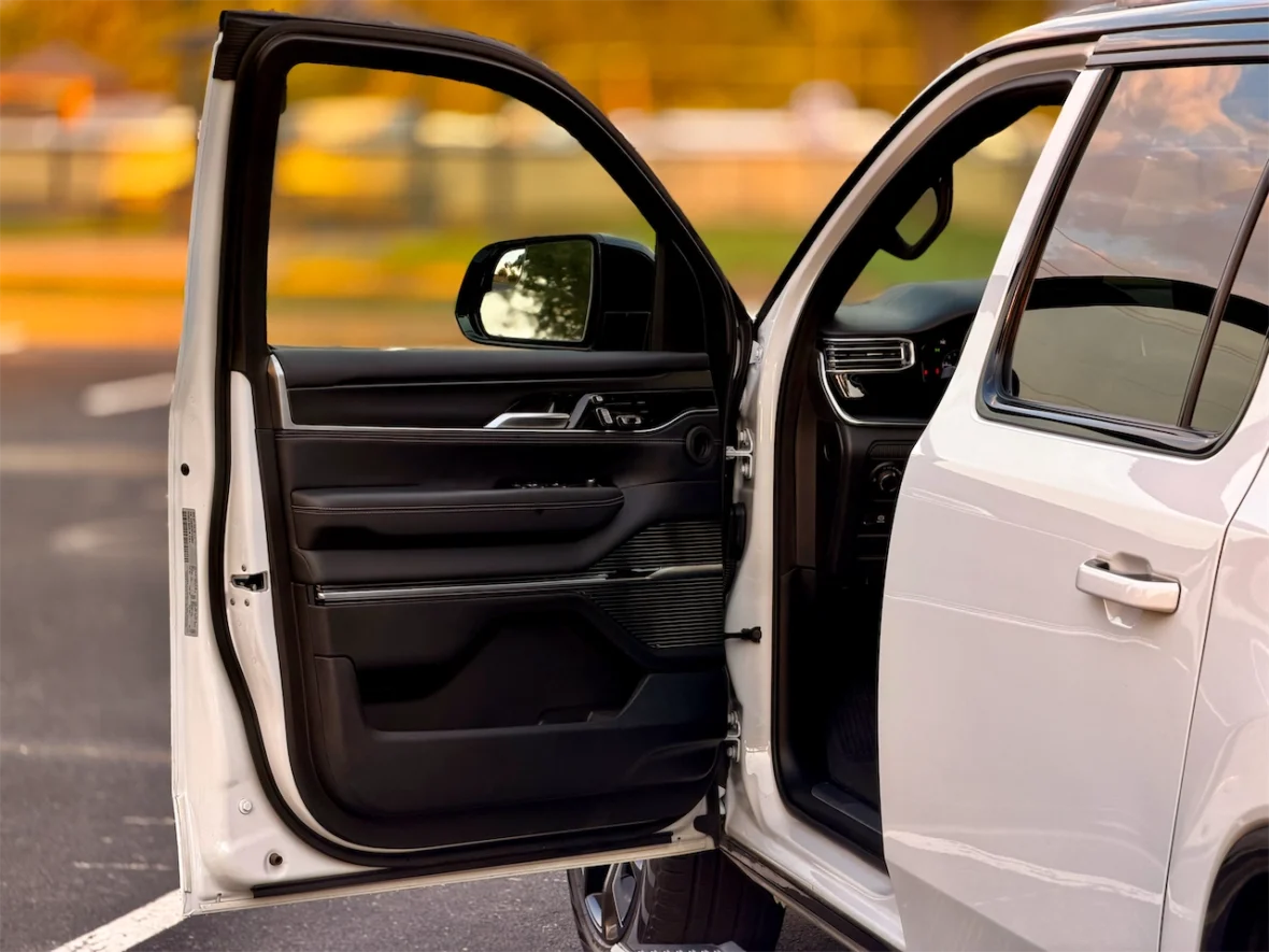 Interior view of the 2026 Jeep Grand Wagoneer L with the driver's door open, showing the seats and dashboard.