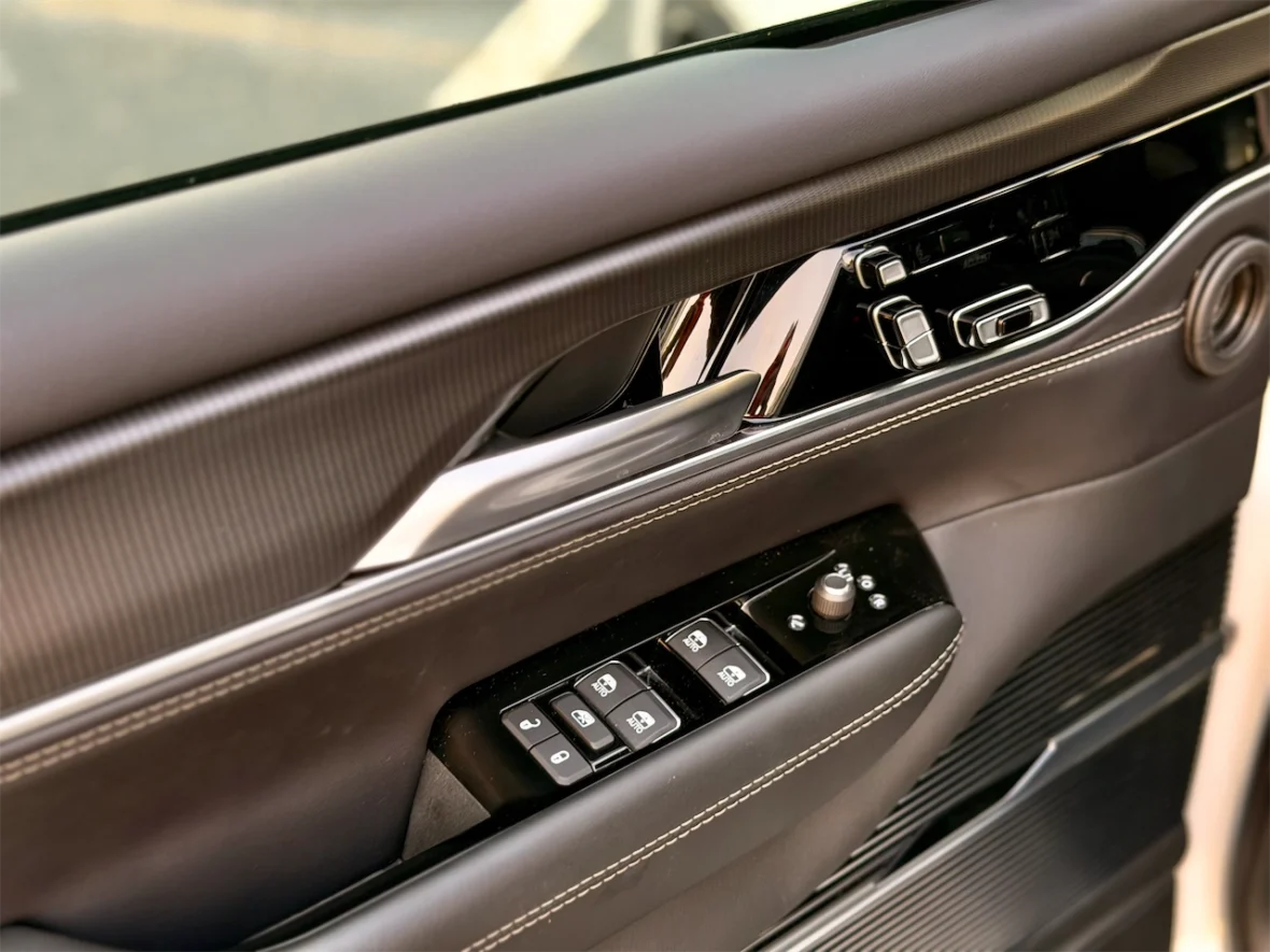 Close-up of a car door panel featuring window control buttons and sleek metallic accents.