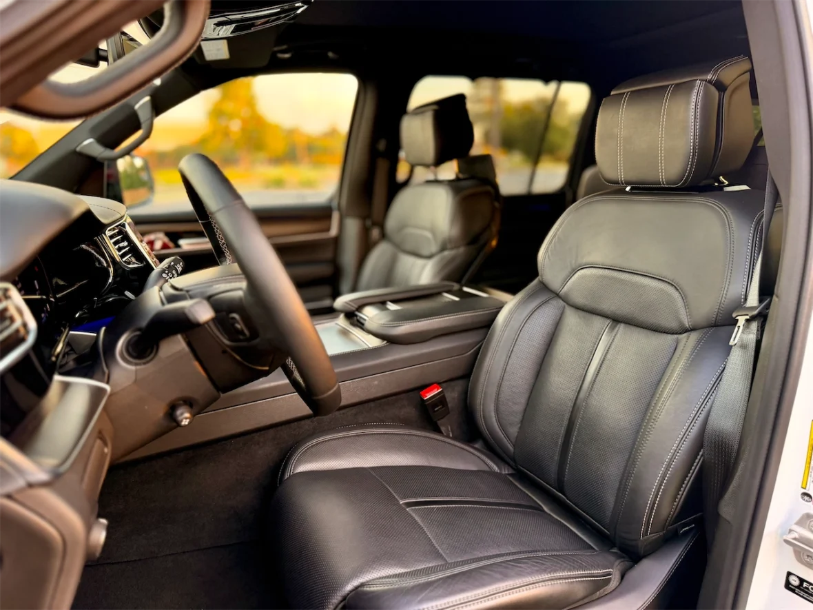 Interior view of a vehicle showcasing luxurious black leather seats and a modern dashboard with a steering wheel.