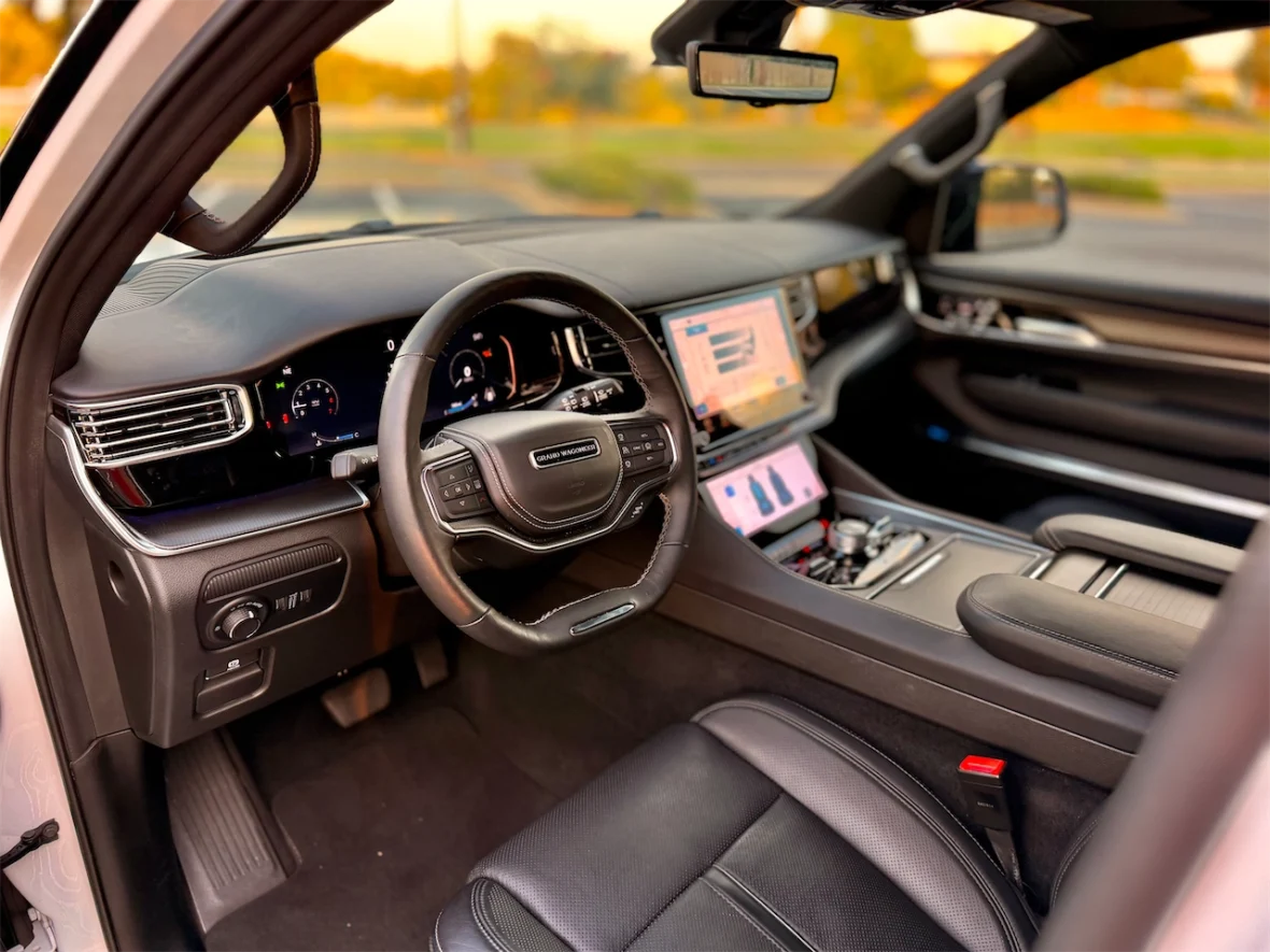 Interior view of a luxury SUV featuring a modern dashboard, steering wheel, and touchscreen display, showcasing advanced technology and leather seating.