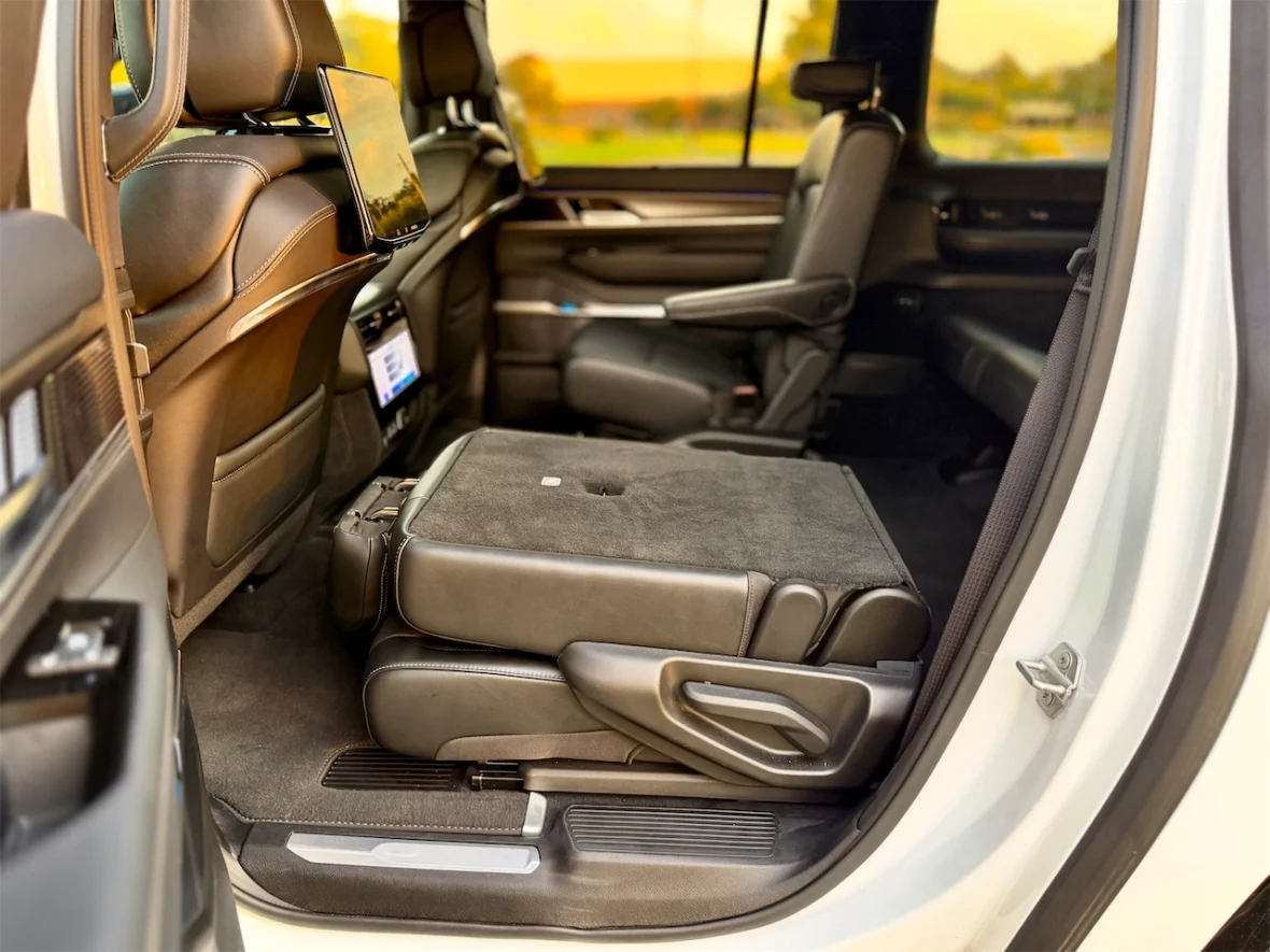 Interior view of a luxury vehicle showing a rear seat with a folded-down seat and an entertainment screen mounted on the front seat back.