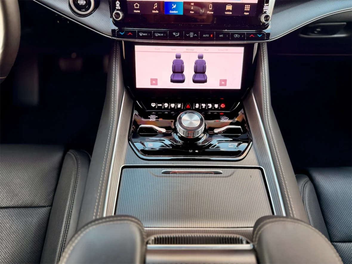 Interior view of a car dashboard featuring a central touchscreen display and control knobs, with visible seating control options shown on the screen.