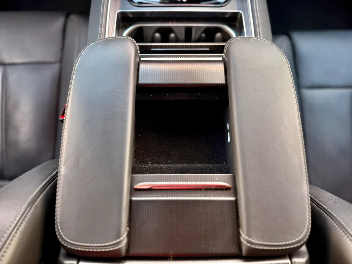 Close-up view of a vehicle's center console with black leather armrests and a storage compartment.