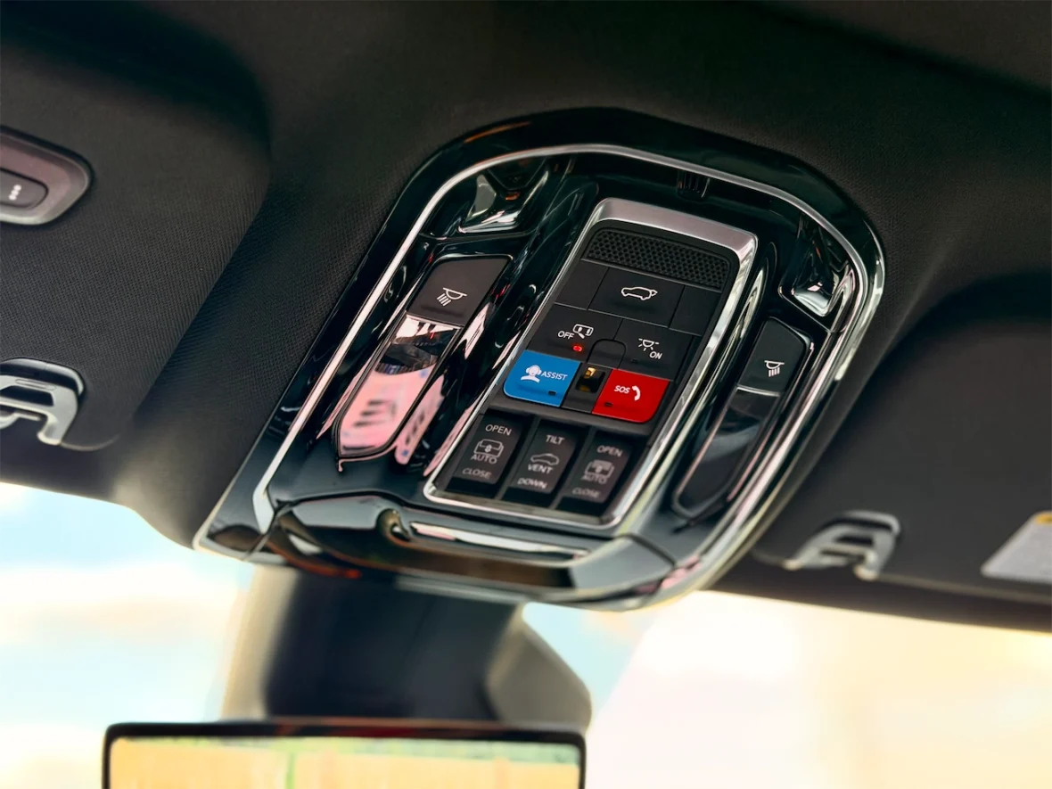 Close-up of a car's interior overhead console with various control buttons, including those for light, sunroof, and safety features.