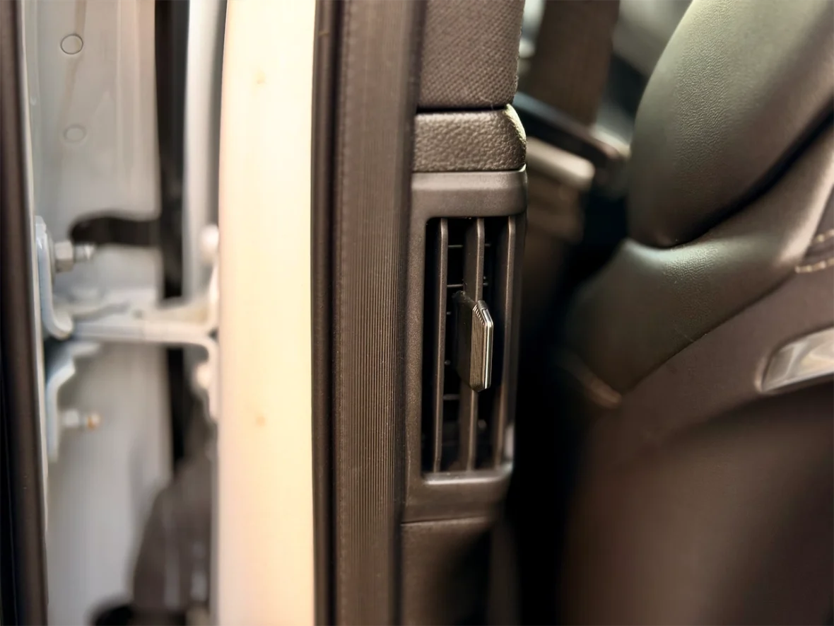 Close-up of a car door interior showing the ventilation grille and a part of the seat.