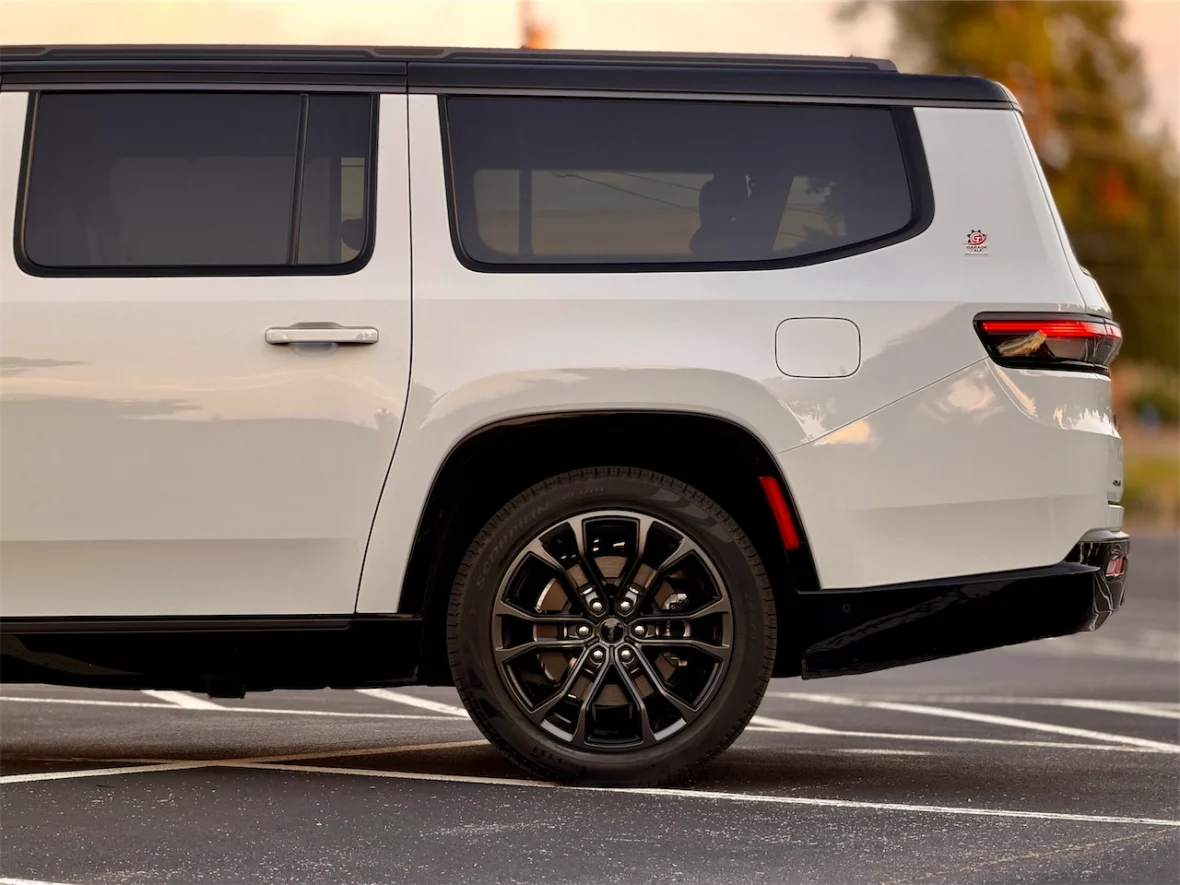Side view of the 2026 Jeep Grand Wagoneer L parked in an empty parking lot, showcasing a sleek design and black alloy wheels.
