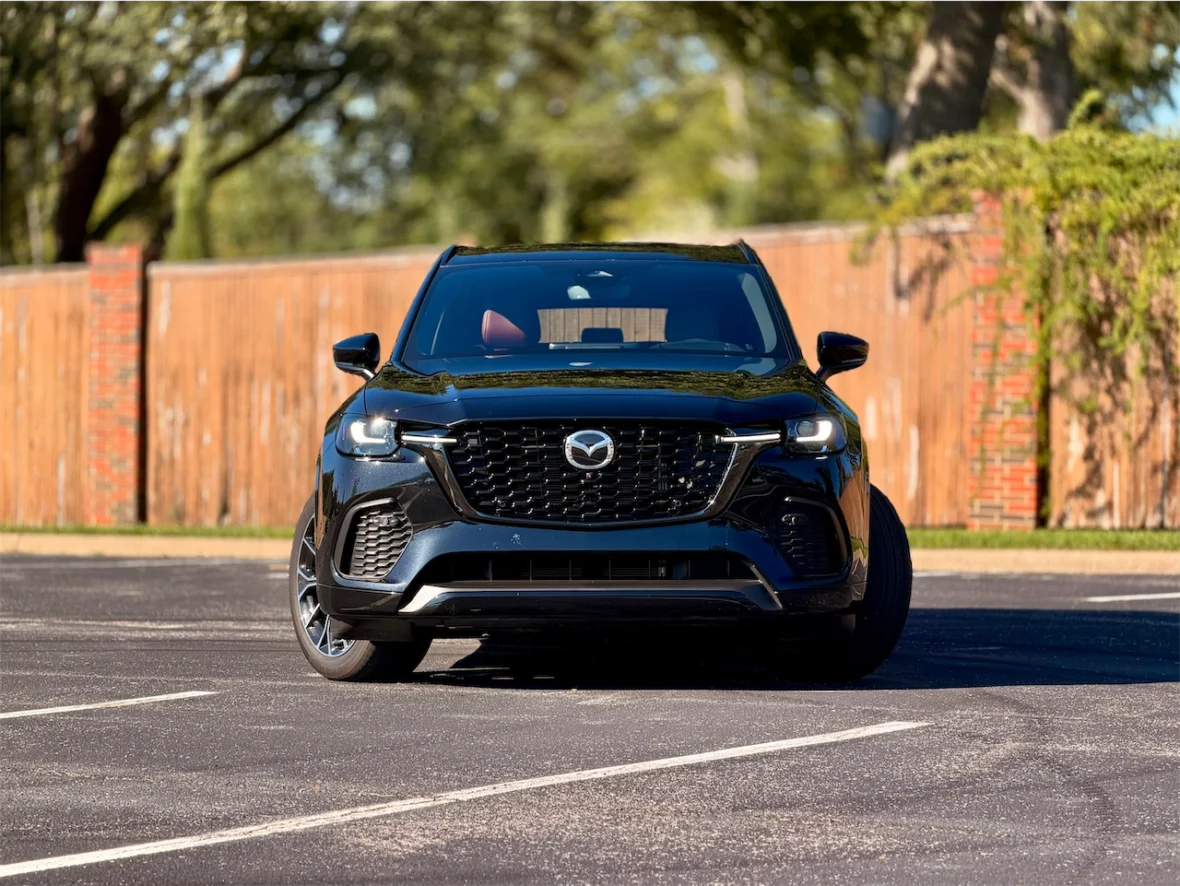 A black Mazda SUV parked in an outdoor setting with a wooden fence in the background.