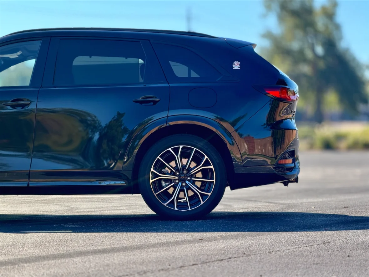 Side view of a black SUV parked on a paved surface, showcasing its sleek design and stylish alloy wheels.