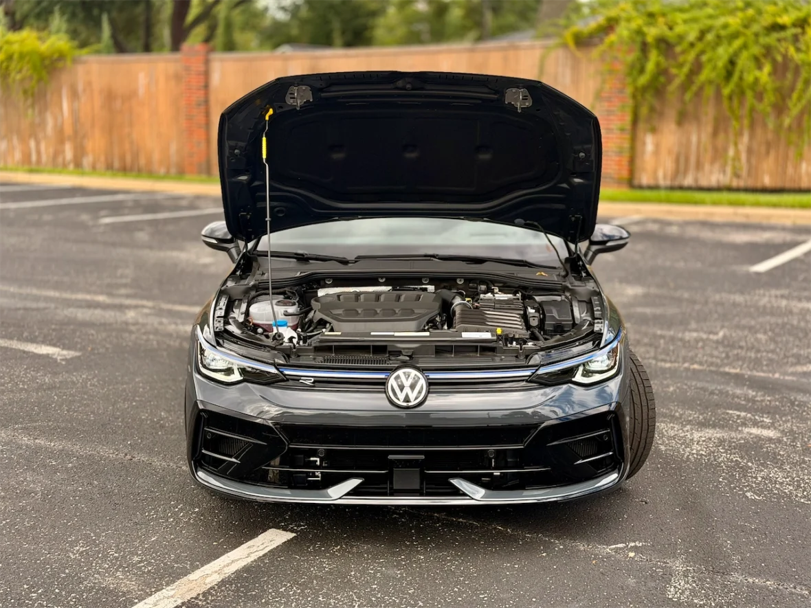 Front view of a Volkswagen car with the hood open, showcasing the engine and various components underneath.