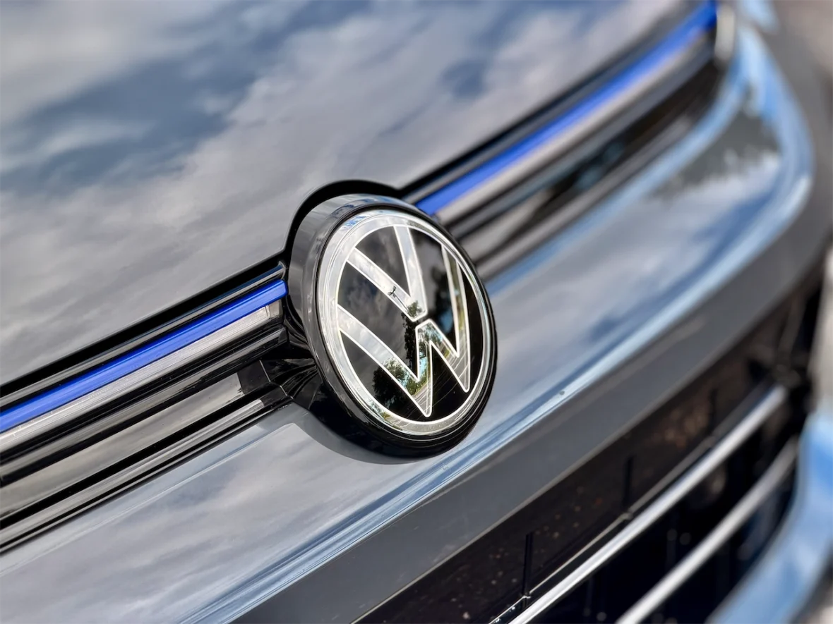 Close-up of a Volkswagen logo on a glossy black vehicle grille with blue accents.