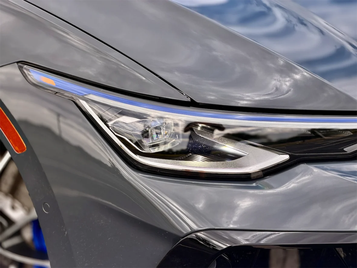 Close-up of a sleek gray car's headlight, showcasing modern design elements and lighting features.