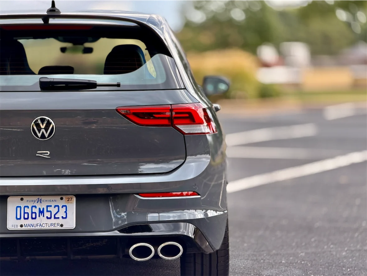 Rear view of a gray Volkswagen car, showcasing the logo, taillights, and dual exhaust pipes.
