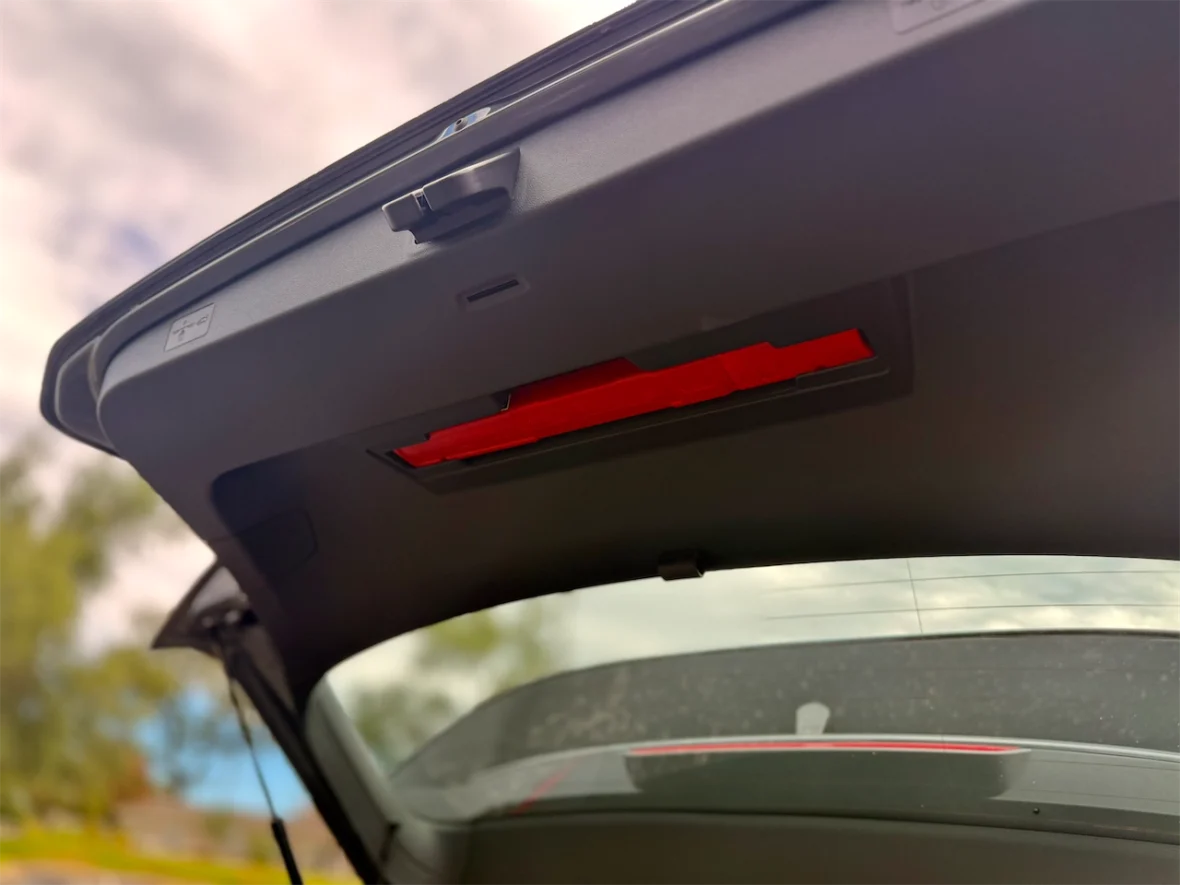 Interior view of a vehicle's trunk lid showing a red light and controls for trunk operation.
