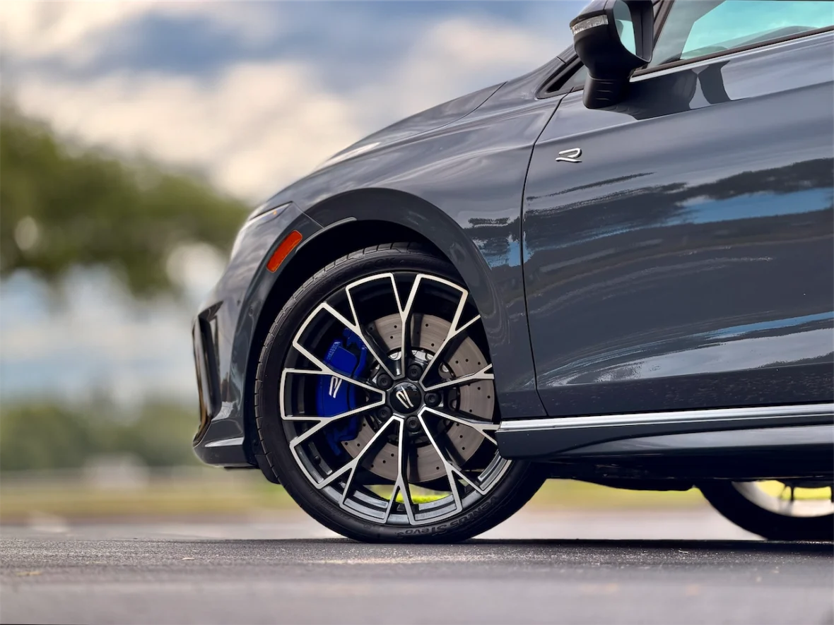 Close-up of a sleek, modern car wheel showcasing a sporty design with a blue brake caliper and intricate alloy spokes.