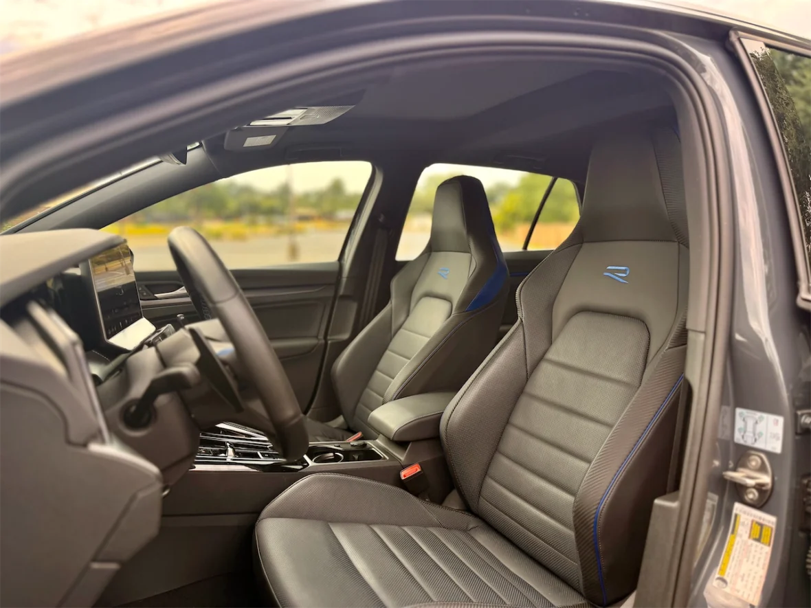 Interior view of a modern car featuring two sporty front seats with blue accents, a steering wheel, and a digital dashboard display.