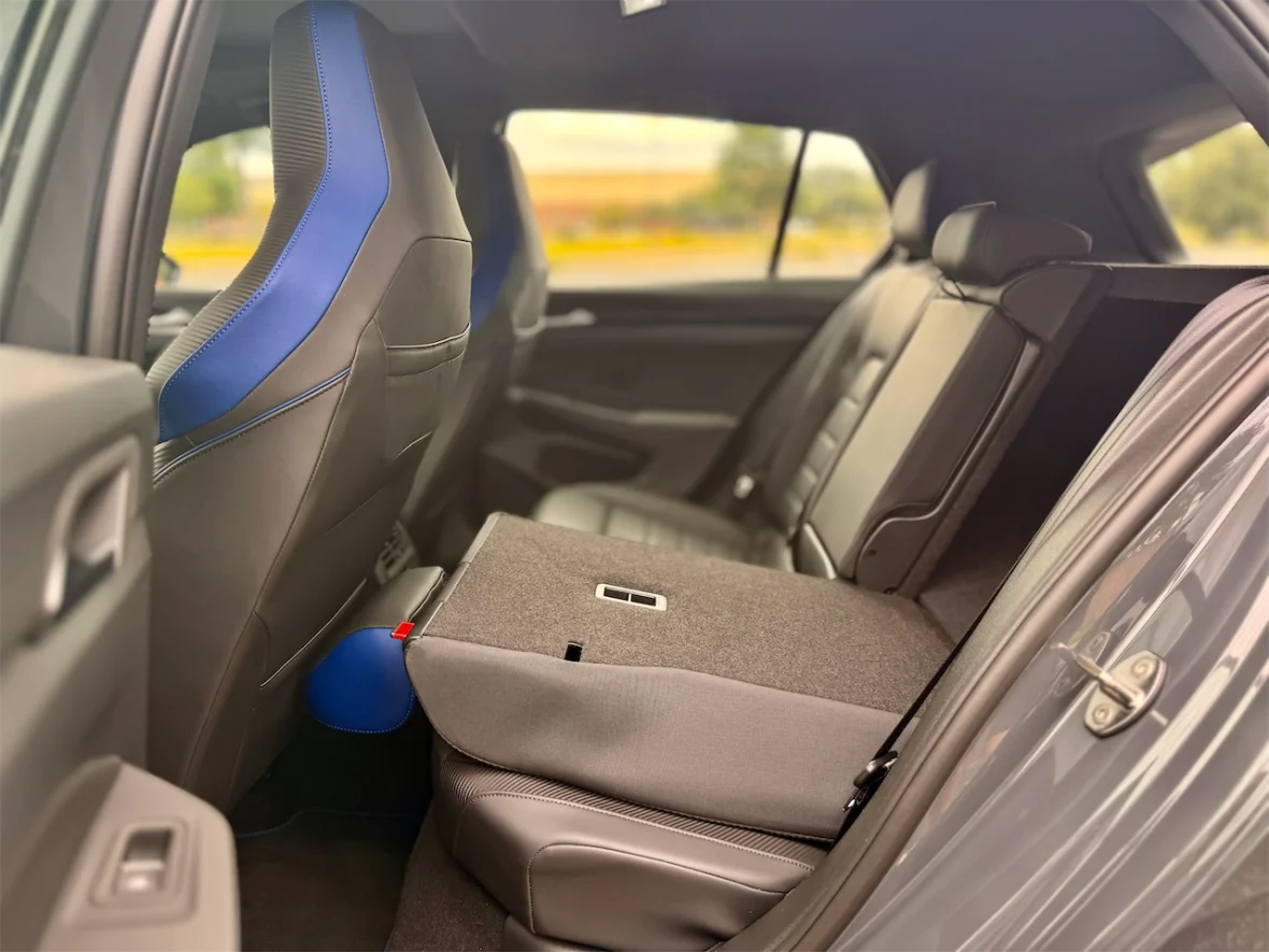 Interior view of a car's back seat, featuring sporty black and blue upholstery and a folded down rear seat for extra cargo space.