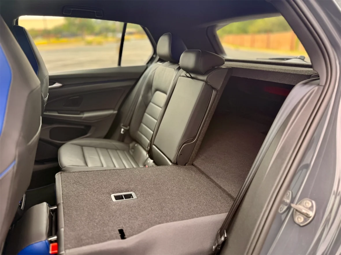Interior view of a car's backseat with black leather seating and a folded-down rear seat, showing spacious cargo area.