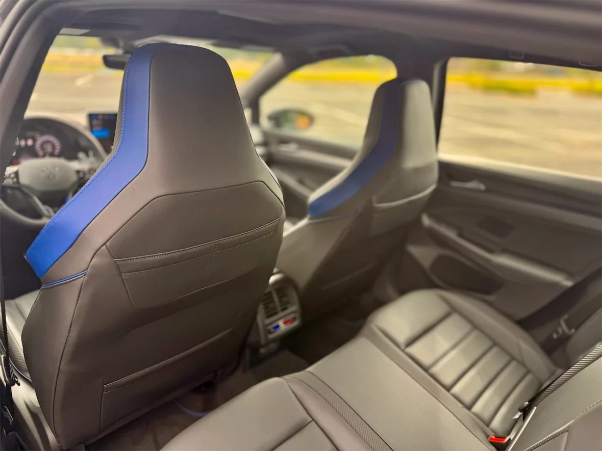 Interior view of a modern car showing the back seats with blue-accented black leather upholstery.