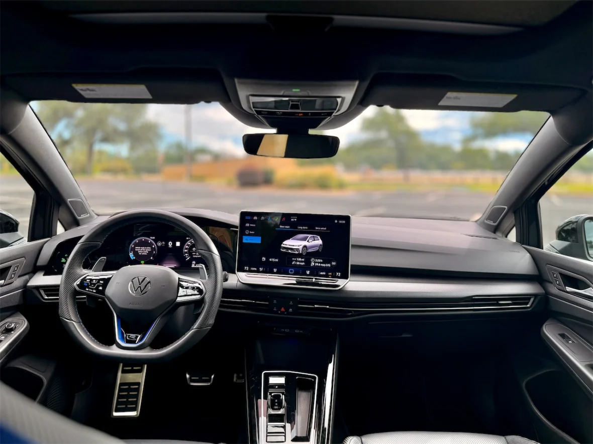 Interior view of a Volkswagen car, showcasing the steering wheel, dashboard, and infotainment system with a digital display.