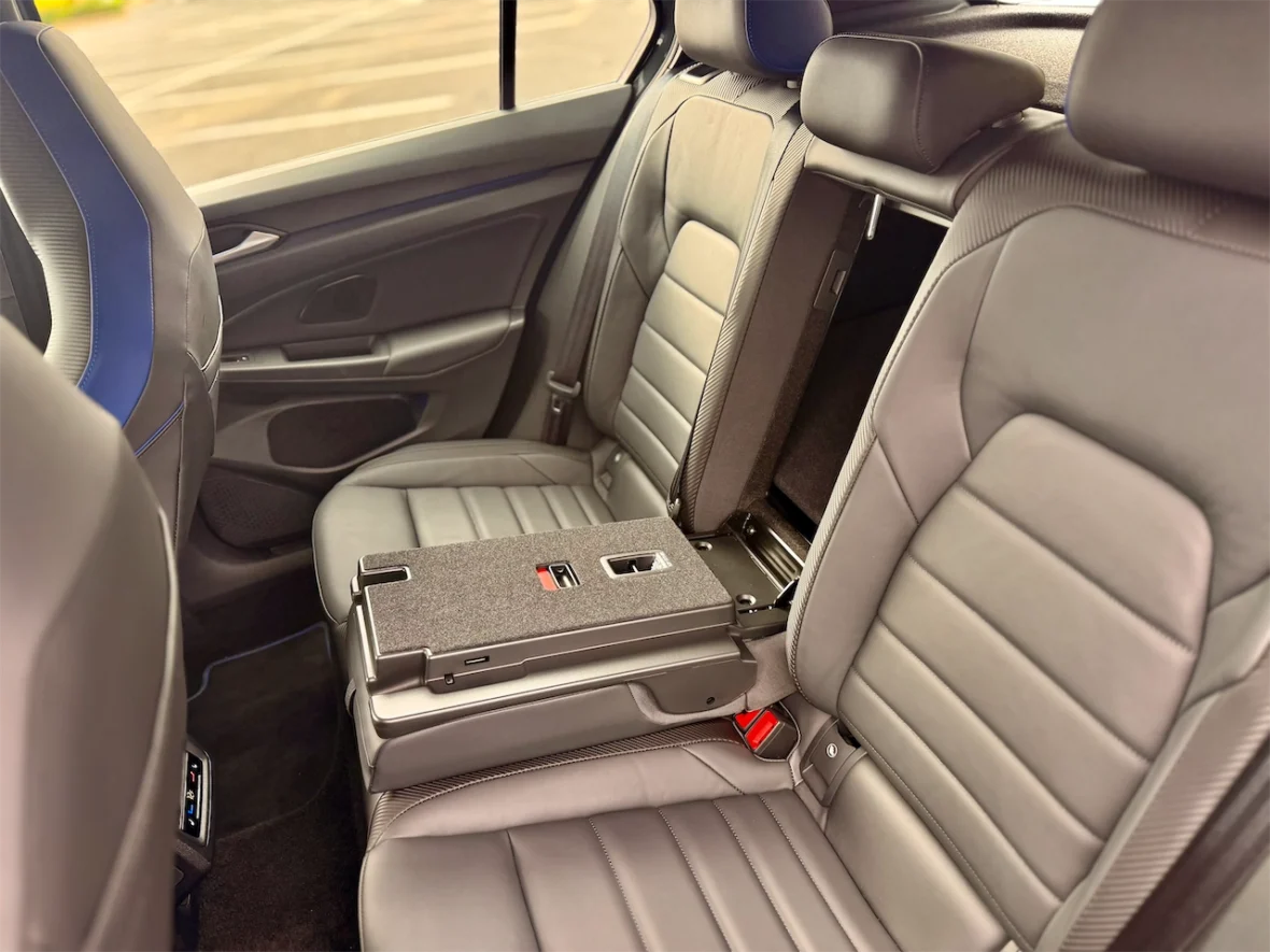 Interior view of a modern car's backseat showcasing two leather seats with a fold-down armrest and cup holder.