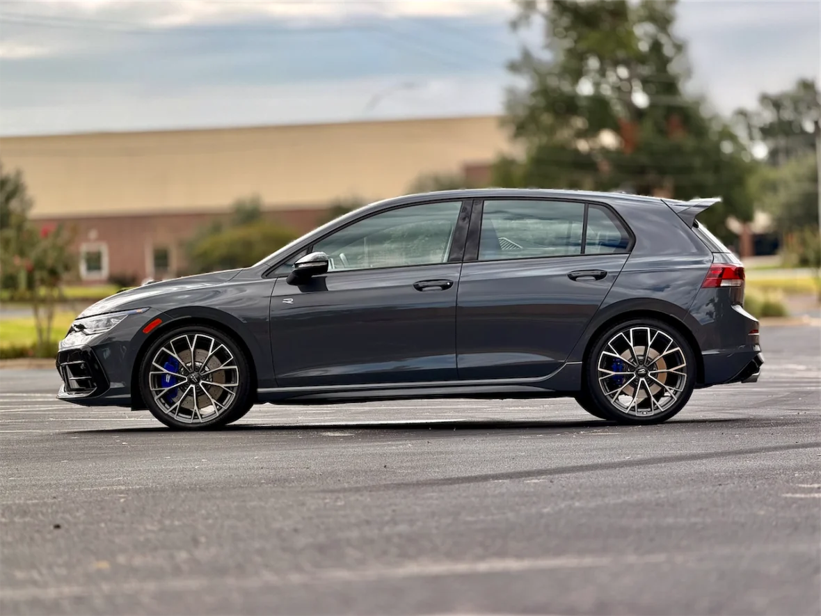 A sleek gray hatchback car parked in a lot, showcasing its sporty design and alloy wheels.