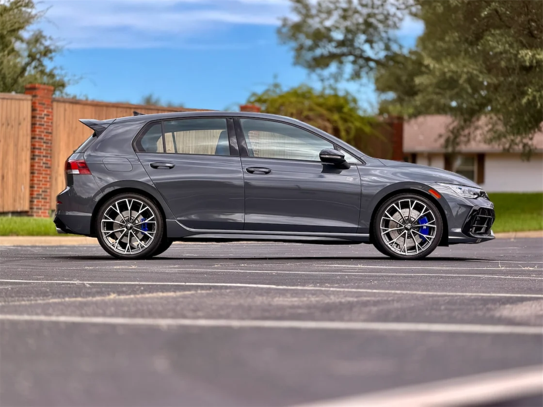 A sleek gray hatchback parked in a lot, showcasing its sporty design with distinctive alloy wheels and an aerodynamic profile.