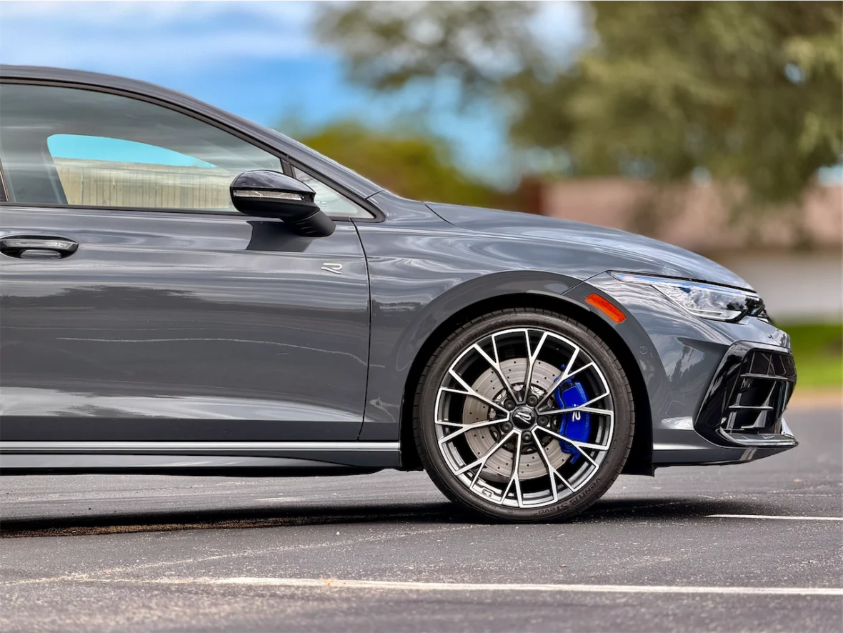 Side view of a gray sports car showcasing detailed alloy wheels and brake calipers.