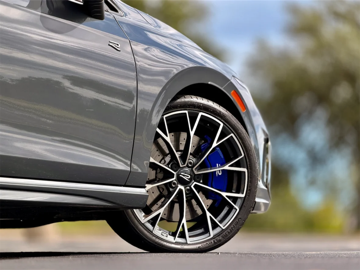 Close-up of a gray car with a stylish alloy wheel featuring a blue brake caliper.