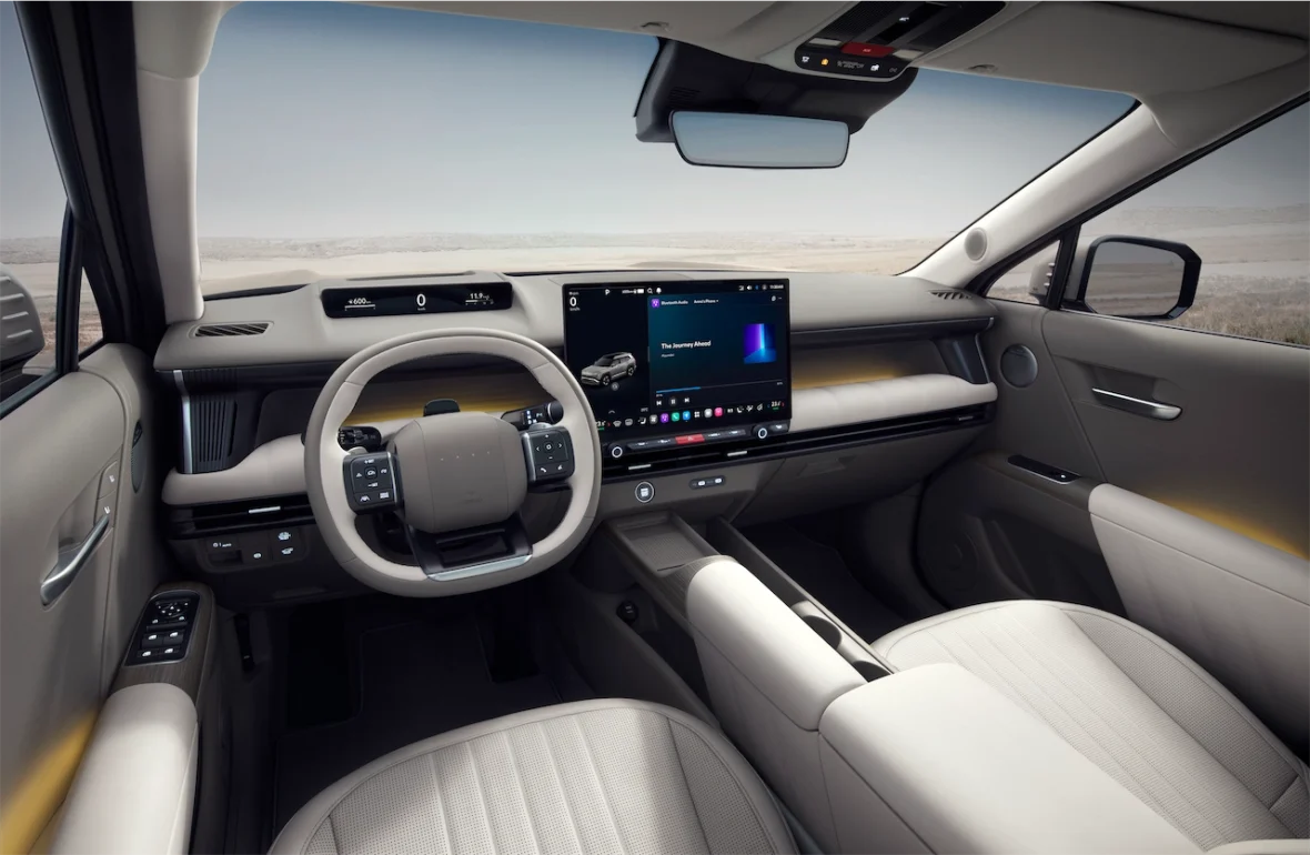 Interior view of a modern car dashboard, featuring a steering wheel, digital display, and plush seats in light colors.