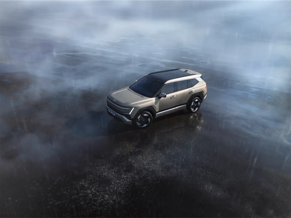 A sleek, modern SUV parked on a wet surface, surrounded by mist and rain.