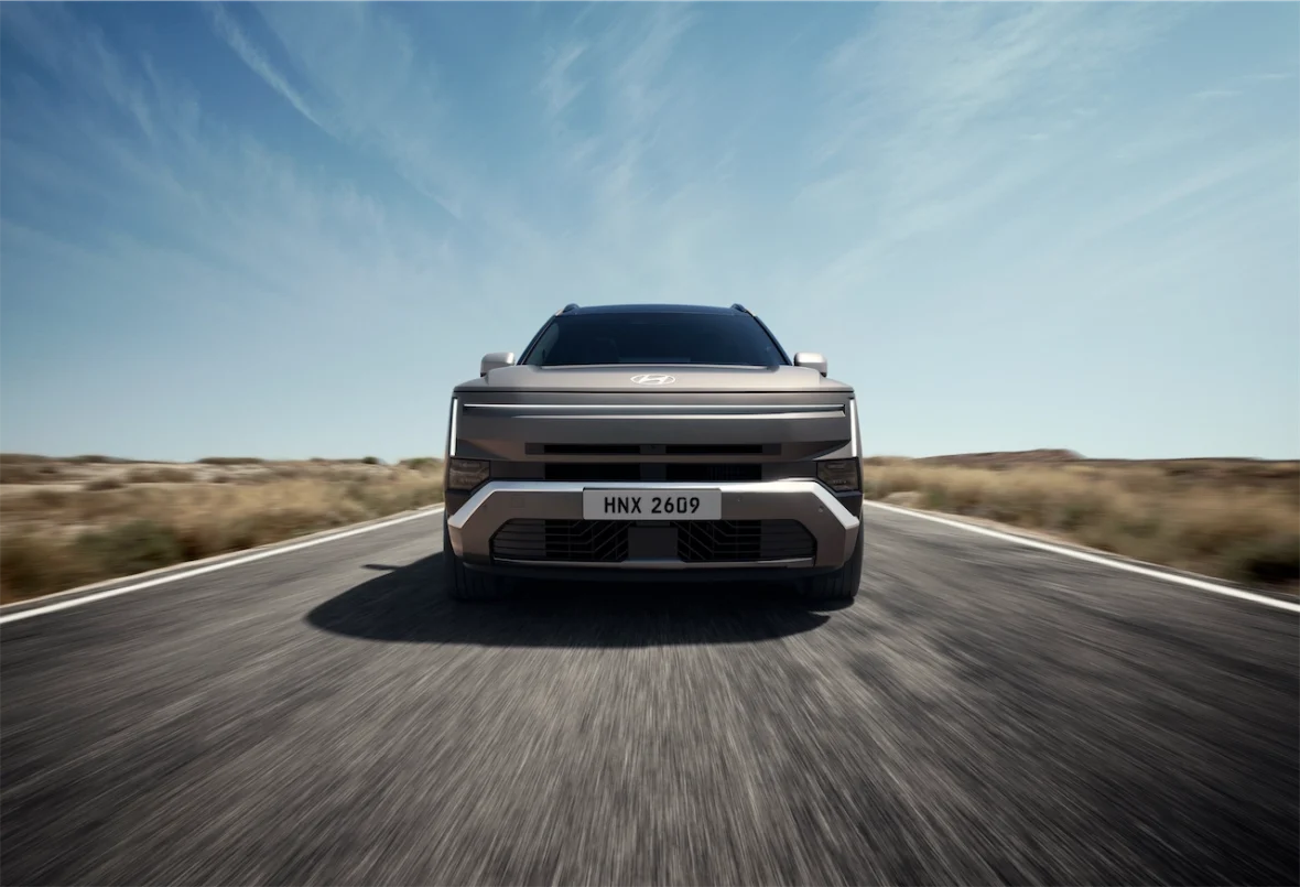 Front view of a modern SUV parked on an empty road with a clear blue sky in the background.