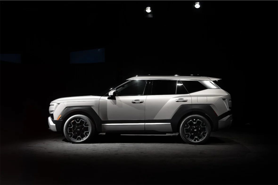 A white SUV showcased in a dark setting, highlighting its modern design and angular features.