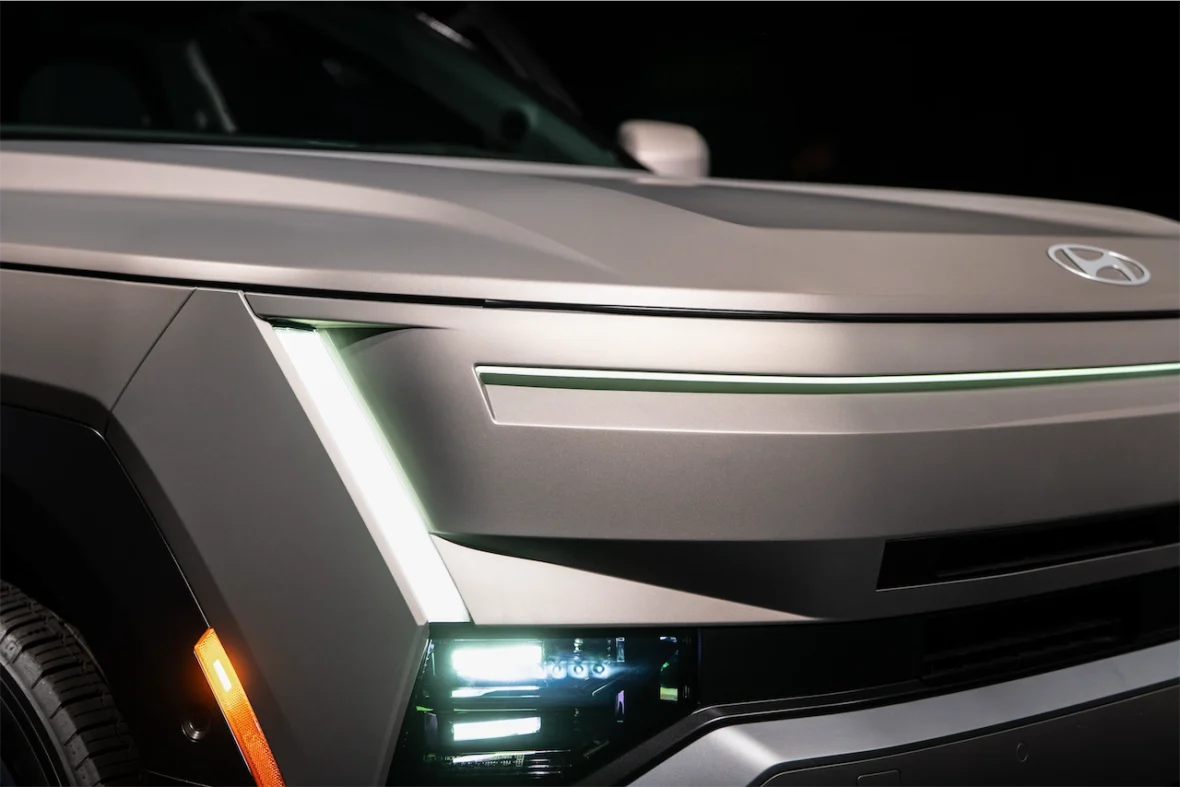 Close-up of a modern vehicle's front, highlighting its sleek design, headlight features, and the car manufacturer's logo.