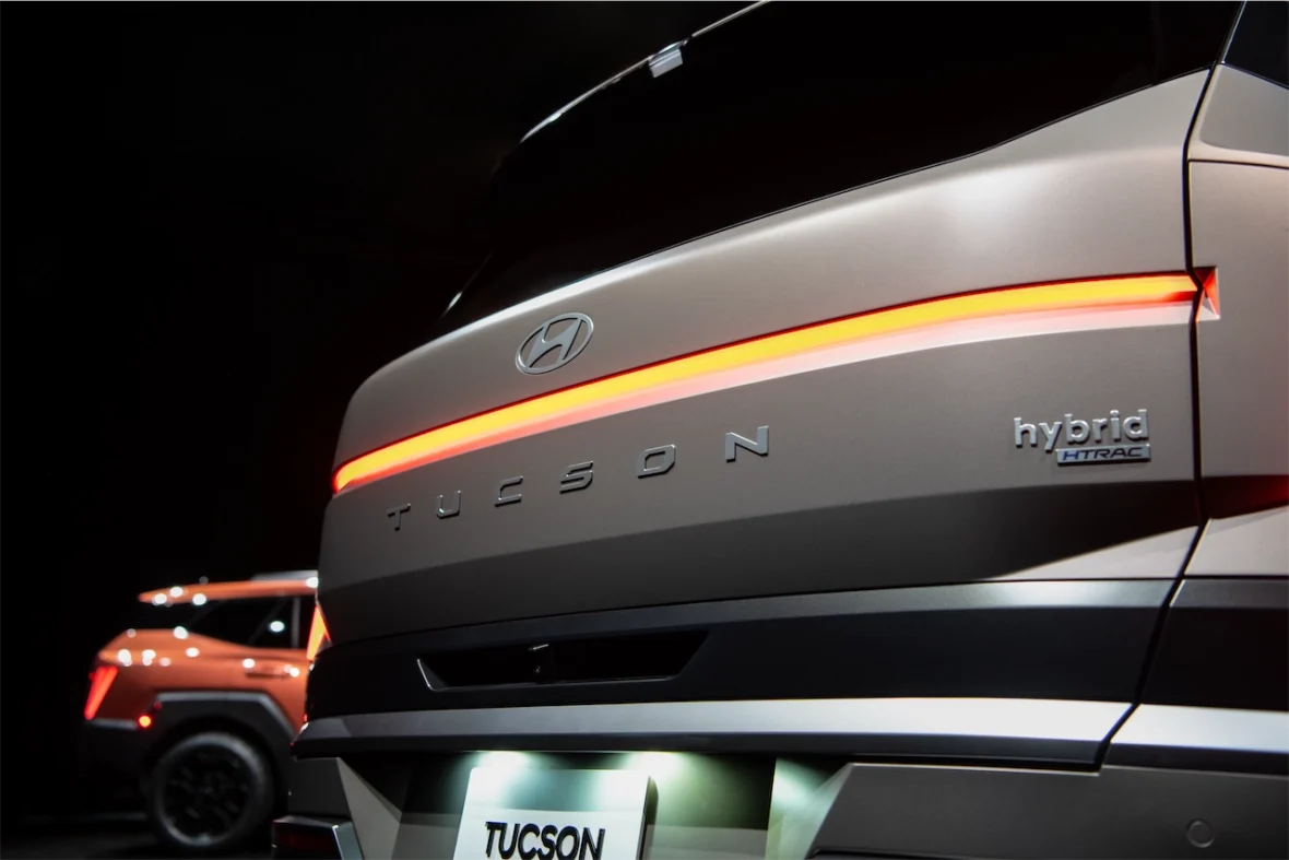 Close-up view of the rear of a Hyundai Tucson hybrid SUV, featuring a sleek design with a glowing taillight and the model name displayed prominently.